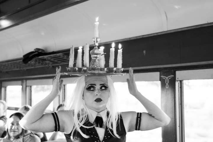 Person balancing a candelabra with lit candles on head inside a train.