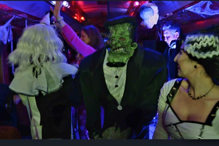 People in Halloween costumes on a decorated train with cobwebs and eerie lighting.