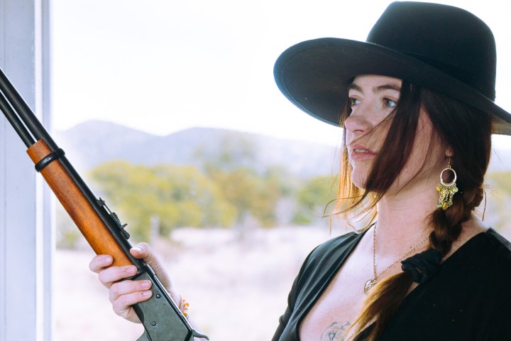 a woman wearing a hat and holding a gun